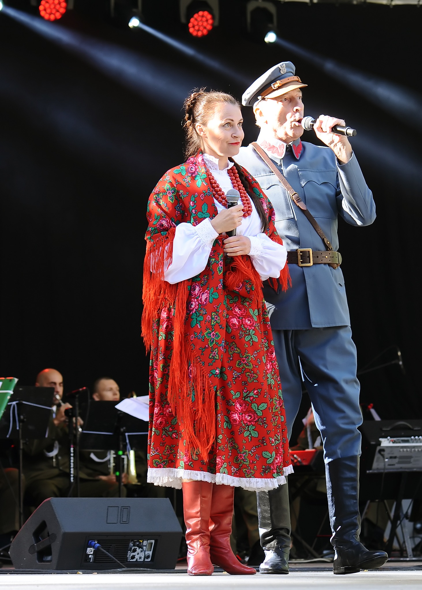 Zdjęcie przedstawia parę artyst&oacute;w, śpiewających. Kobieta ubrana jest w&nbsp;str&oacute;j ludowy, mężczyzna w&nbsp;odświętny mundur wojskowy.
