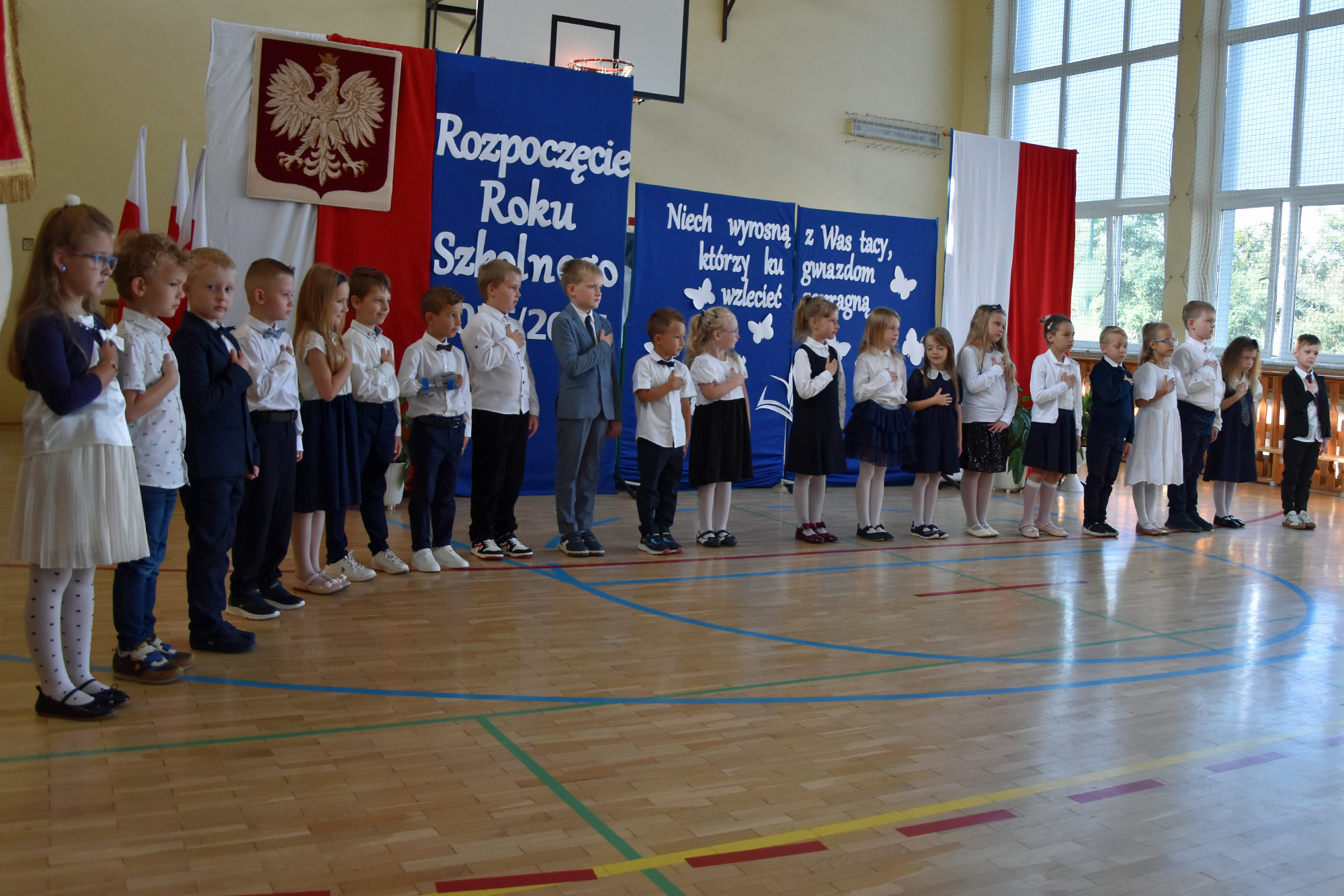 Zdjęcie przedstawia pierwszoklasist&oacute;w składających ślubowanie pierwszoklasisty. Dzieci ubrane są na&nbsp;galowo.