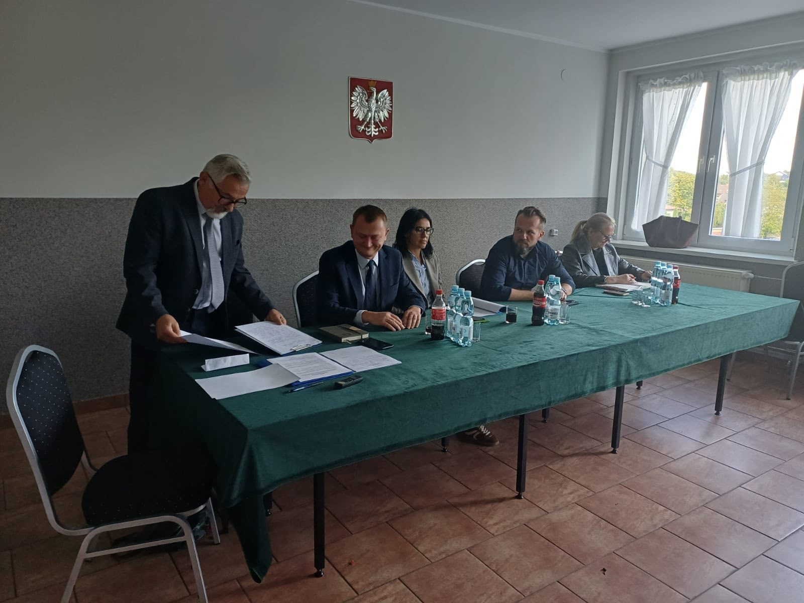 Zdjęcie pokazuje st&oacute;ł gości podczas zebrania wiejskiego.