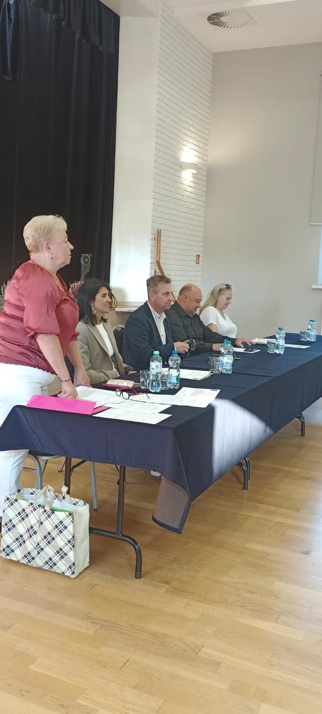 Zdjęcie przedstawia gości siedzących przy stole, przemawia sołtys Sączowa.